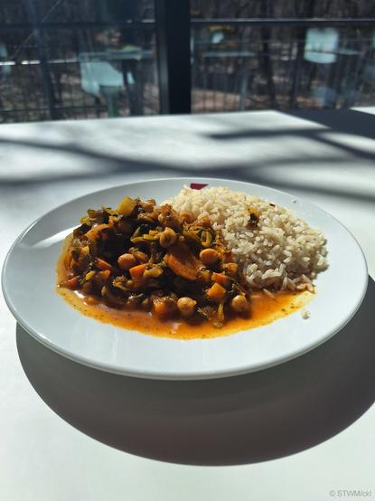 Auf dem Bild ein Eintopf mit Spinat, Kichererbsen, Süßkartoffeln in tomatisierter Gemüsebrühe. Daneben Reis.