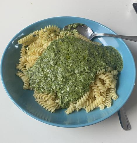 Ein Teller, gut gefüllt mit Spiralnudeln und darüber eine grüne Soße.