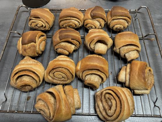 Brown cinnamon rolls laying on a cooling rack on a gray countertop.