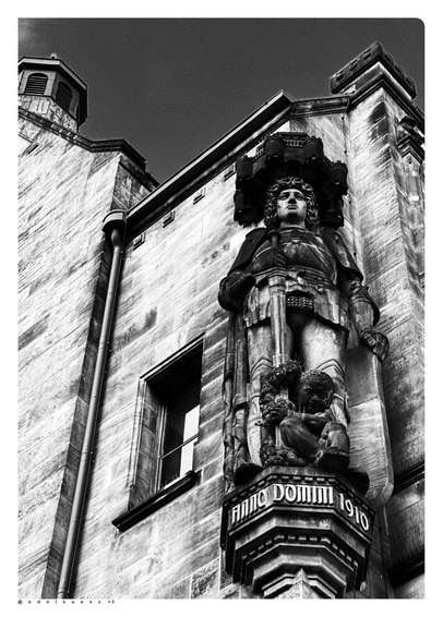 Schwarzweißfotografie: hohe Eckfigur am neuen Rathaus, Darstellung des Roland (Symbol des Streiters für städtische Freiheit und Gerichtsbarkeit, mit Schwert) schmuckvolle Steinmetzarbeit, 1910
