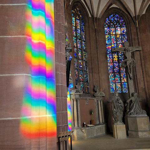 Hohe bunte Fenster durch die die Sonne eine Säule in Regenbogenfarben hüllt