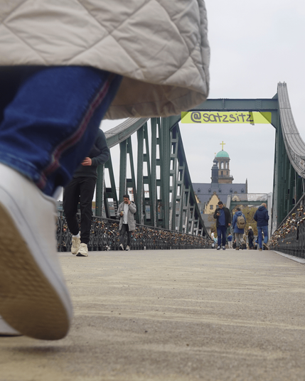 Eiserner Steg (Brücke) auf Bodenhöhe fotografiert: Füße, die drüberlaufen