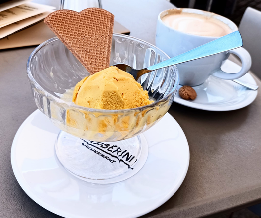 In einer Glasschale eine Kugel gelbes Sorbet und eine herzförmige Waffel
