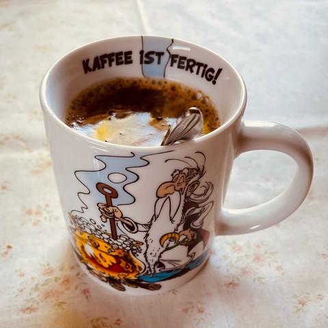 Foto einer Tasse mit Miraculix-Motiv, auf dem Innenrand oben steht „Kaffee ist fertig!“
