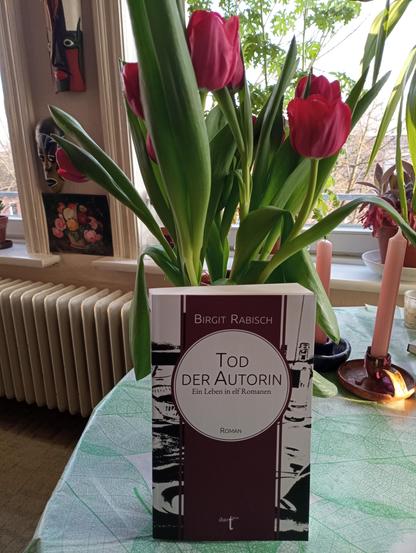 Der Roman "Tod der Autorin" vor einem Tulpenstrauß