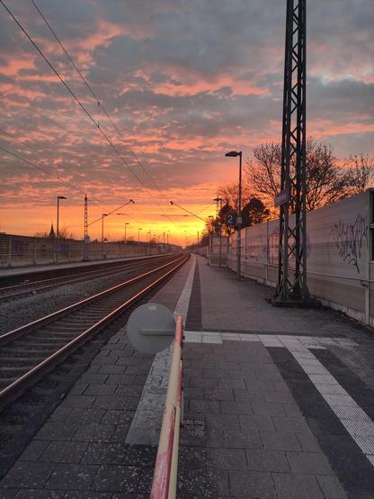 Fiery sunset with  golden glowing clouds over a small rural train station.
