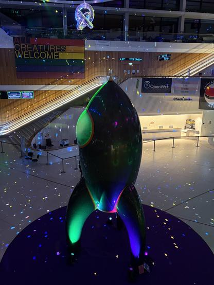 Photo of the CCC rocket called Fairydust in an empty entrance hall scattered with thousands of moving lights from the mirror installations.